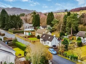 a house with a car parked on a street at Broom Cottage in Newtonmore