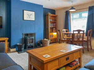 a living room with a table and a blue wall at Broom Cottage in Newtonmore