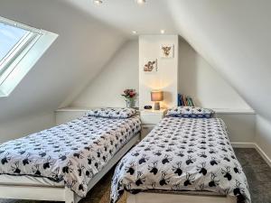 a attic bedroom with two beds and a window at Broom Cottage in Newtonmore +28 photos