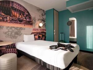 a hotel room with a large white bed and blue walls at ibis styles Paris Montmartre Batignolles in Paris