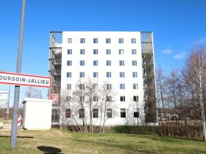 a white building with a street sign in front of it at Ibis Bourgoin Jallieu Medipole in Bourgoin
