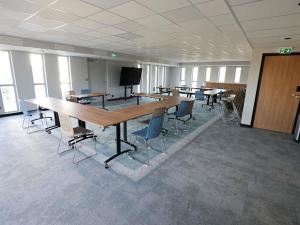 a conference room with tables and chairs and a television at Ibis Bourgoin Jallieu Medipole in Bourgoin