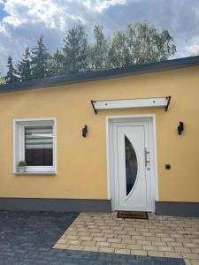 a yellow building with a white door and two windows at Ferienhaus Friedrich 22 in Kolkwitz