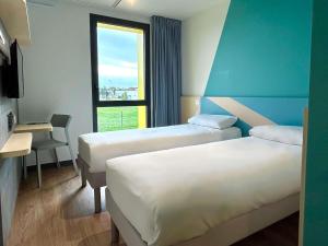 a hotel room with two beds and a window at ibis budget Loudéac Vélodrome in Loudéac