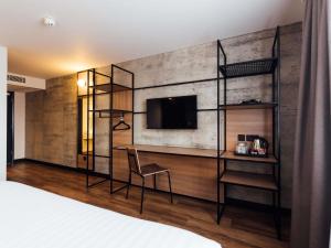 a bedroom with a wall with a tv and a chair at ibis Coleraine Riverside in Coleraine