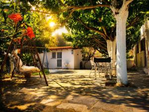 a playground with two chairs and a tree at Yfantis Sakis Apartment's in Erateini