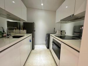 a kitchen with white cabinets and a sink and a dishwasher at Sky Apart-Hotel klcc in Kuala Lumpur