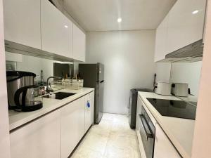a kitchen with white cabinets and a black refrigerator at Sky Apart-Hotel klcc in Kuala Lumpur