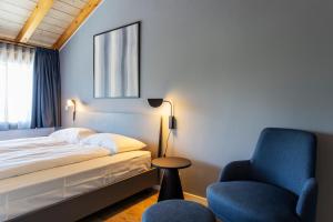 a bedroom with a bed and a blue chair at Osteria Ascona in Ascona