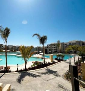 a large swimming pool with palm trees and buildings at Zahra-Northed Chalet in El Alamein