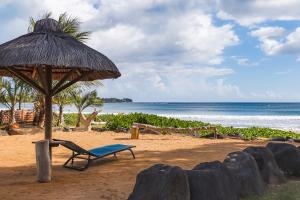 a beach with a chair and an umbrella and the ocean at NEW Beachfront 3-bedrooms Apartment in Tamarin, Ocean Legend in Tamarin