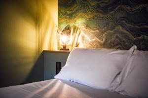 a bed with a pillow and a lamp on a wall at Les Gens Heureux Appartement GLAZ in Paimpol