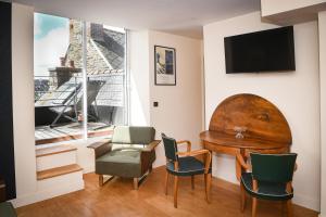 a living room with a table and chairs and a window at Les Gens Heureux Appartement GLAZ in Paimpol