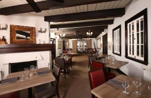 a restaurant with wooden tables and chairs and a fireplace at Sir Sam's Inn & Spa in Haliburton