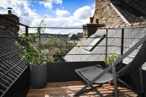 a chair sitting on the balcony of a house at Les Gens Heureux Appartement GLAZ in Paimpol