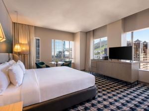 a hotel room with a bed and a flat screen tv at Pullman Cape Town City Centre in Cape Town