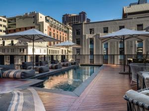 a pool on the roof of a building with umbrellas at Pullman Cape Town City Centre in Cape Town