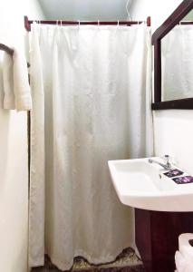a bathroom with a white shower curtain and a sink at Chale's House Hotel in San Juan del Sur