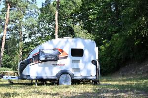 a small white trailer parked in a field at Woodlands camping in Greatham +13 photos