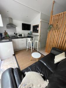 a living room with a black couch and a kitchen at Studio cosy avec piscine privative in Saint-Sernin +29 photos