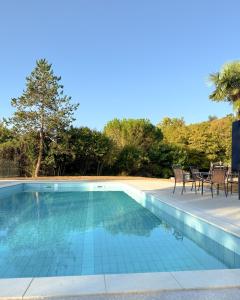 a swimming pool with chairs and trees in the background at Domaine des Chais in Thénac