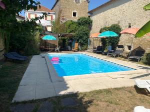 a swimming pool with chairs and umbrellas next to a building at Oasis de Vic in Vic-Fezensac