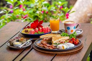 a table with two plates of breakfast food and a drink at Le Panpurie Koh Lanta Resort - Near the Beach in Ko Lanta