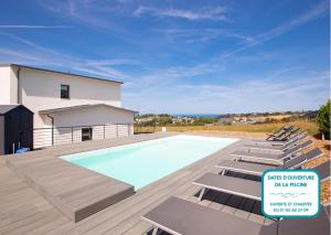 a swimming pool with lounge chairs next to a house at Villa neuve avec piscine vue sur mer pour 9 in Pléneuf-Val-André