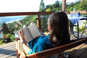 a woman sitting in a chair reading a book at BELVEDERE - das BIO HOTEL Garni & SuiteHotel am Edersee ! Unser Geschenk für Sie, auch die GästeCard GrimmHeimat! in Waldeck