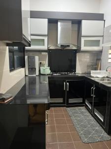 a kitchen with black cabinets and a black counter top at Suzys homestay in Kuantan