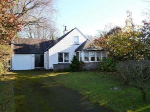 a white house with a garage and a yard at Calluna Cottage in Rockcliffe