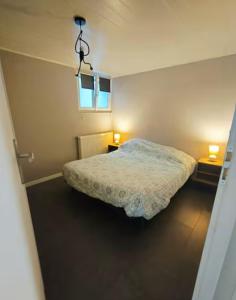 a small bedroom with a bed and two lamps at Appartement Bois de doubs in Pontarlier