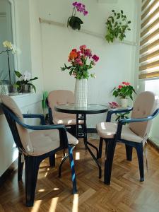 a table with chairs and a vase of flowers at Apartman Orhideja in Višegrad