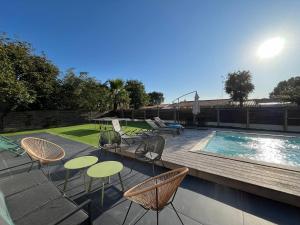 a patio with chairs and tables next to a swimming pool at Villa Palmyra - Piscine Privée in La Teste-de-Buch