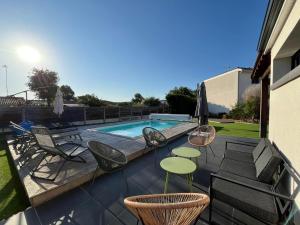 a patio with chairs and tables and a swimming pool at Villa Palmyra - Piscine Privée in La Teste-de-Buch