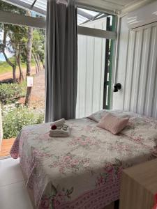 a bedroom with a bed and a large window at Pousada Jardim Encantado - Suítes em Container na cidade do Cristo Protetor - Encantado RS in Encantado