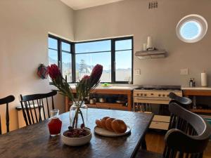 a kitchen with a table with bread and flowers on it at Beach Paradise in Muizenberg