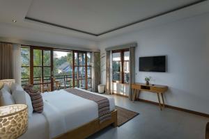a bedroom with a large bed and a television at Villa Mirah Ubud in Ubud