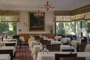 a restaurant with white tables and chairs and a chandelier at Parkhotel Flora am Schluchsee in Schluchsee