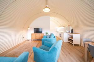 a living room with blue chairs and a kitchen at Cultybraggan Hut 35 in Comrie