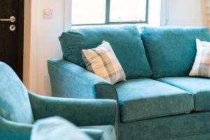 a blue couch with pillows sitting next to a chair at Cultybraggan Hut 35 in Comrie +21 photos
