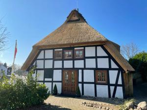a black and white building with a thatched roof at Zur Schleikate in Boren