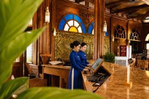 two women standing in front of a counter with a laptop at Le' VIVA Resort Mui Ne in Mui Ne