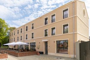 a large tan building with a patio in front of it at Kaffeegarten Am Mühlwerder in Halle an der Saale