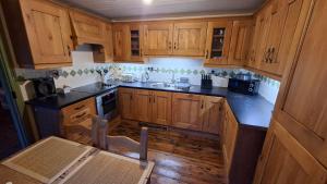 a kitchen with wooden cabinets and a sink and a table at The Point by the Sea in Carraroe