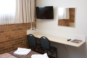 a room with a desk with two chairs and a tv on the wall at Buckaroo Motor Inn in Warwick