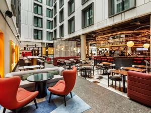 a restaurant with tables and chairs in a building at TRIBE Terminal 2 Manchester Airport by Accor in Manchester Airport