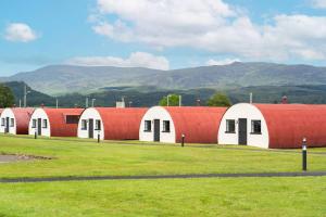 a row of red and white buildings with mountains in the background at Cultybraggan Hut 37 in Comrie
