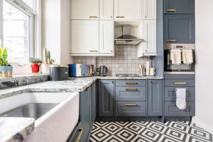 a kitchen with blue and white cabinets and a sink at Walpole Bay Sea Views in Margate