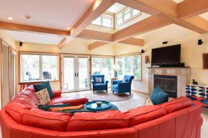 a living room with a red couch and a fireplace at Beautiful backyard pool deeded beach rights in Truro